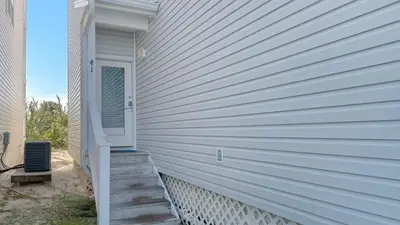 a white house with a door and stairs on it at Float Away in Panama City Beach