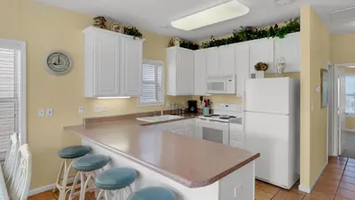 a kitchen with white cabinets and a white refrigerator at Float Away in Panama City Beach