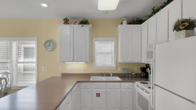 a white kitchen with white cabinets and a sink at Float Away in Panama City Beach