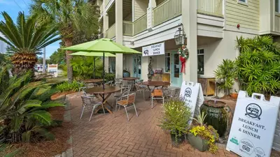 a patio with tables and chairs and a green umbrella at Grand Isle 202 in Santa Rosa Beach