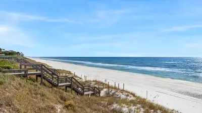 a beach with wooden benches and the ocean at Grand Isle 202 in Santa Rosa Beach