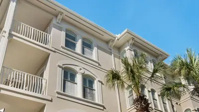 a white building with palm trees in front of it at Villas At Seagrove B201 - Emerald Dunes in Santa Rosa Beach