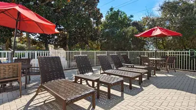 a group of tables and chairs with red umbrellas at Villas At Seagrove C401 in Santa Rosa Beach