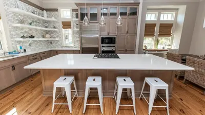 a kitchen with a large white island with four stools at Tranquility at A La Paix in Panama City Beach