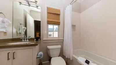 a bathroom with a toilet and a sink and a window at Tranquility at A La Paix in Panama City Beach