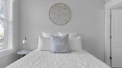 a white bedroom with a bed with a love pillow at Monterey Condos A201 in Panama City Beach