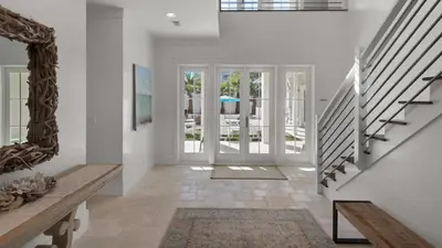 a hallway with white walls and a staircase with a mirror at Emotional Rescue in Inlet Beach