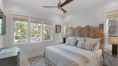 a bedroom with a bed with white walls and windows at Emotional Rescue in Inlet Beach