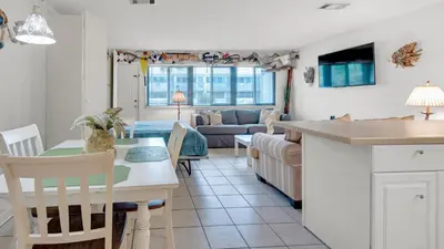 a kitchen and living room with a table and a couch at Hidden Beach 103 in Santa Rosa Beach