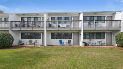 a large white building with chairs and a yard at Hidden Beach 103 in Santa Rosa Beach