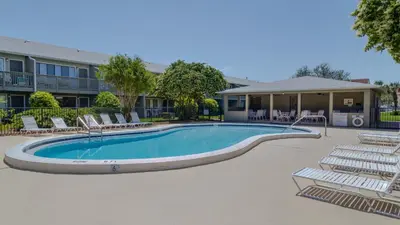 a swimming pool with lounge chairs in front of a building at Hidden Beach 103 in Santa Rosa Beach