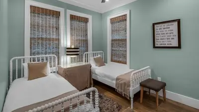 a bedroom with two beds and a chair and two windows at Sea Echo in Santa Rosa Beach