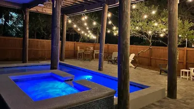 a swimming pool in a backyard at night with lights at Khalee-sea in Seacrest