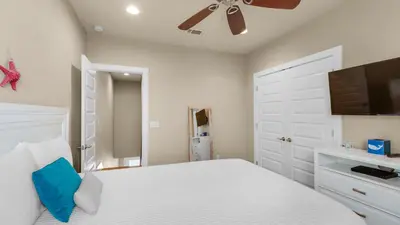 a bedroom with a white bed and a ceiling fan at Khalee-sea in Seacrest