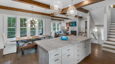 a kitchen with white cabinets and a dining room with a table at Ocean Park in Santa Rosa Beach