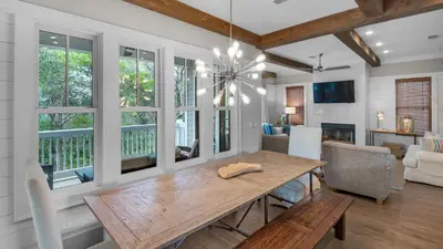 a dining room with a table and a living room at Ocean Park in Santa Rosa Beach
