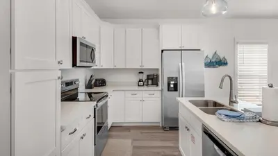 a white kitchen with white cabinets and a refrigerator at Seabreeze in Panama City Beach