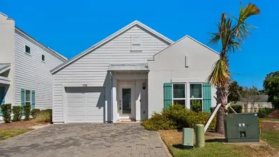 a white house with a palm tree in front of it at Seabreeze in Panama City Beach