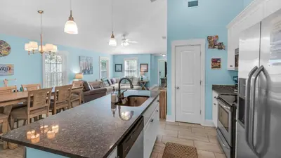 a kitchen and dining room with blue walls at Sandy Teauxs in Panama City Beach