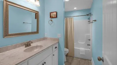 a bathroom with a sink and a toilet and a mirror at Sandy Teauxs in Panama City Beach