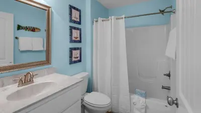 a bathroom with a sink and a toilet and a mirror at Sandy Teauxs in Panama City Beach
