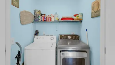 a small kitchen with a stove and a washing machine at Sandy Teauxs in Panama City Beach