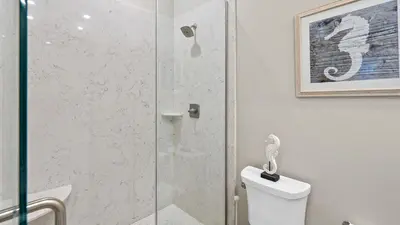 a bathroom with a shower and a toilet with a glass door at Seasational in Panama City Beach