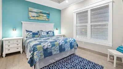 a bedroom with blue walls and a bed and a window at Seasational in Panama City Beach