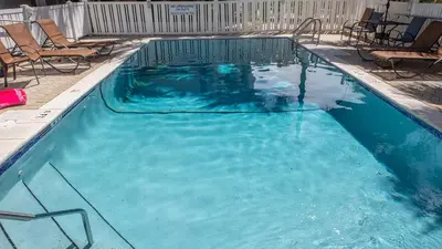 a swimming pool with blue water and chairs in it at Seagrove By The Sea IIC in Santa Rosa Beach