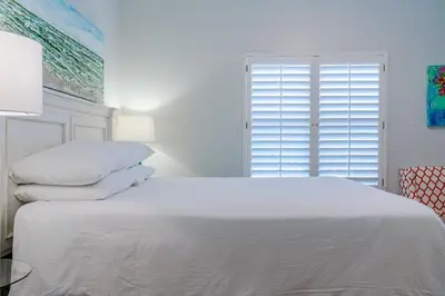 a bedroom with a white bed with pillows and a window at Legacy 402-Flemingo's Paradise in Seagrove Beach