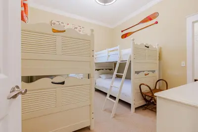 a bedroom with two bunk beds and a kitchen at Shore Thing in Rosemary Beach