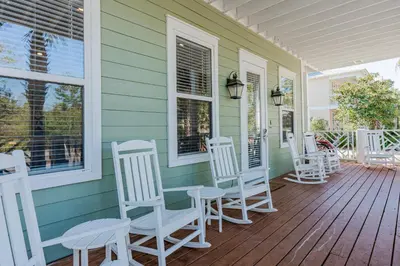 a porch with white rocking chairs on a house at Shore Thing in Rosemary Beach