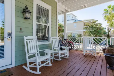 a porch with white rocking chairs on a house at Shore Thing in Rosemary Beach
