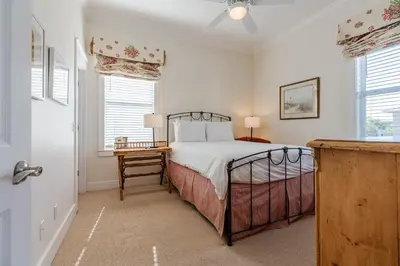 a bedroom with a bed and a table and windows at Shore Thing in Rosemary Beach