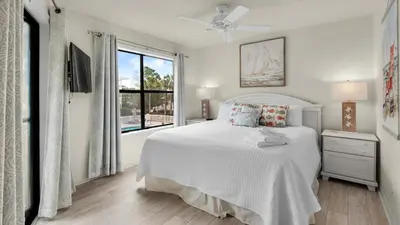 a white bedroom with a bed and a window at Beachwood Villas 10H - Bliss at Beachwood in Santa Rosa Beach