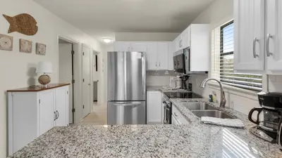 a kitchen with white cabinets and a stainless steel refrigerator at Beachwood Villas 10H - Bliss at Beachwood in Santa Rosa Beach