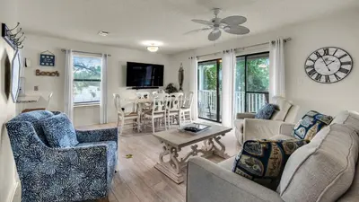a living room with a couch and chairs and a clock at Beachwood Villas 10H - Bliss at Beachwood in Santa Rosa Beach