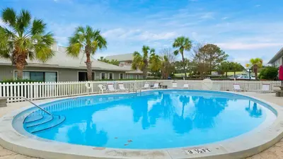 a large swimming pool with palm trees and a fence at Beachwood Villas 10H - Bliss at Beachwood in Santa Rosa Beach