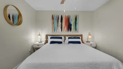 a white bedroom with a large bed with blue pillows at Eastern Shores 106 in Santa Rosa Beach