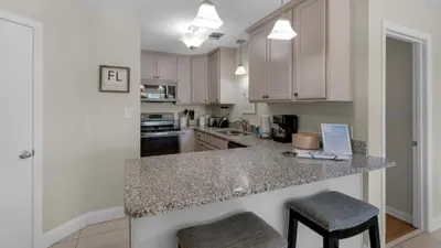 a kitchen with white cabinets and a counter with stools at Beachwood Villas 11E - SE Seagrove in Santa Rosa Beach