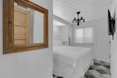 a white bedroom with a bed and a mirror at Sand Cliffs 107 in Seacrest