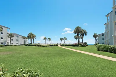 a large lawn with palm trees and condos at Sand Cliffs 107 in Seacrest