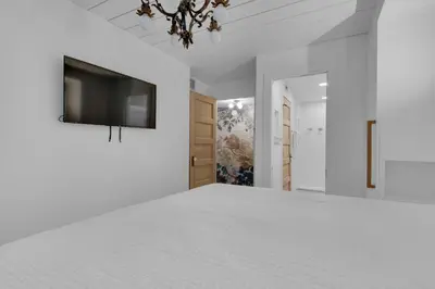 a white bedroom with a bed and a flat screen tv at Sand Cliffs 107 in Seacrest