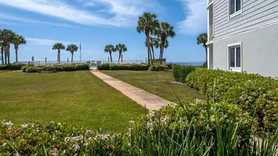a house with a lawn and palm trees at Sand Cliffs 106 in Seacrest