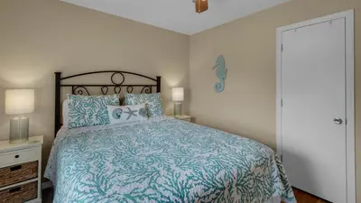 a bedroom with a bed with a blue comforter at Beachwood Villas 10C - A Wave From It All in Santa Rosa Beach