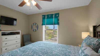 a bedroom with a bed with a ceiling fan and a window at Beachwood Villas 10C - A Wave From It All in Santa Rosa Beach