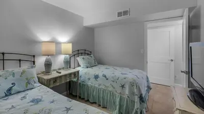 a bedroom with two beds and a table with a lamp at Sand Cliffs 117 in Seacrest