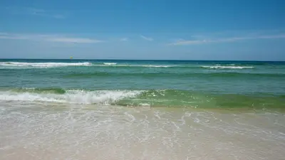 a beach with a small wave in the ocean at Beachwood Villas 1D in Santa Rosa Beach