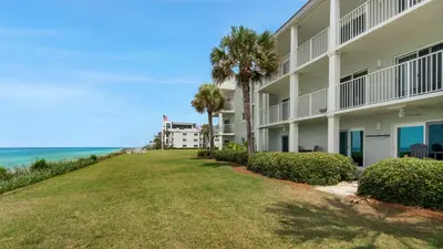 a view of a building with palm trees and the ocean at Sand Cliffs 118 in Seacrest