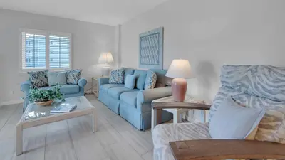 a living room with a blue couch and a table at Sand Cliffs 214 in Seacrest